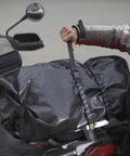 Person securing large bag on motorcycle with Beefy Heavy Duty Reflective Adjustable Cargo Stretch Strap For Motorcycles And ATVs 18 To 60 Inch 100 Lb Capacity Quick Release Buckle UV Protected Polyester Built To Last And Keeps Your Paint Safe And Straps Secure