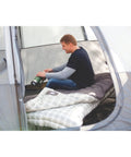 Man sitting inside a tent with a Heritage Big and Tall 10F Flannel Sleeping Bag for Adults Up to 6 Foot 7 Inches Tall Four Season Thermal Insulated and Machine Washable Great for Camping Hunting Guests and More spread out next to him.