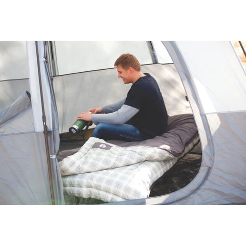 Man sitting inside a tent with a Heritage Big and Tall 10F Flannel Sleeping Bag for Adults Up to 6 Foot 7 Inches Tall Four Season Thermal Insulated and Machine Washable Great for Camping Hunting Guests and More spread out next to him.