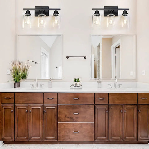 Three Light Black Vanity Light Fixtures With Clear Glass Shades in bathroom over wooden cabinets and mirror, E26 Base