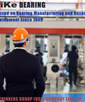 Individual in suit and safety helmet in bearing manufacturing facility, showcasing machinery and work environment.