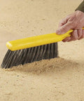 Heavy Duty Eight Inch Counter Cleaning Brush Featuring Flagged Polypropylene Bristles Structural Foam Handle For Smooth Tile Floors Bathrooms And Patios Go To Sweepin Grip Tool on a sandy surface.