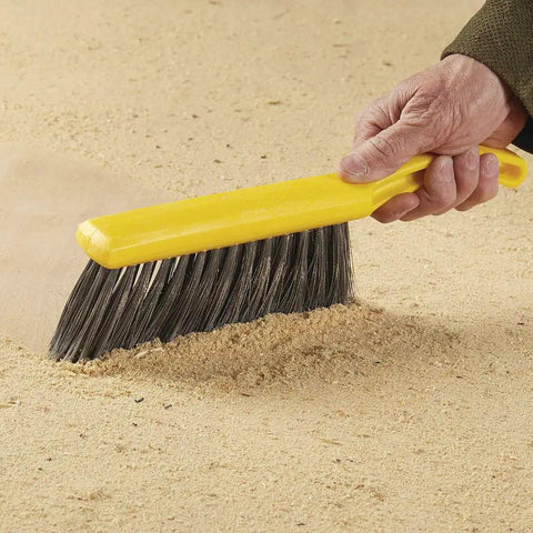 Heavy Duty Eight Inch Counter Cleaning Brush Featuring Flagged Polypropylene Bristles Structural Foam Handle For Smooth Tile Floors Bathrooms And Patios Go To Sweepin Grip Tool on a sandy surface.