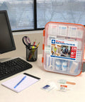 Front view of 24/7 multi-purpose first aid kit in orange-trimmed clear plastic case, 336 pieces