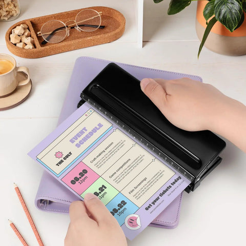 Rugged 6 Hole Paper Puncher With Adjustable Ring Spacing For A5, A6, A7 Formats, in use on a planner page, black