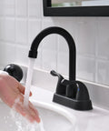 Person washing hands under Matte Black Two Handle Bathroom Sink Faucet With Pop Up Drain And Supply Lines 4 Inch Centerset Design For 2 Or 3 Hole Lavatory Vanity Sleek Modern Fixture With No Fuss Install And Precise Temperature Control.