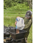 Person filling UTV And ATV Receiver Mount Broadcast Spreader Seeder with seeds, showcasing 80-pound capacity and 12 ft broadcast width.