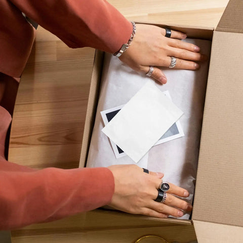 Person packing a box with Adhesive Packing List Envelopes With Window Design For Shipping Docs And Invoices, 100 Pack Self Sealing Poly Bags.
