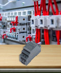 Rail Mounted Switching Power Supply Delivering Knockout DC Stability With A Beefy Smart IC Chip And Copper Transformer on a wooden surface, next to a breaker box.