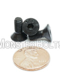 No Nonsense Heavy Duty Number 10-32 By Half Inch Flat Head Socket Cap Screws With Hex Drives next to a penny for size comparison.