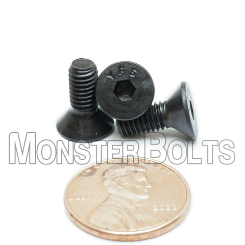 No Nonsense Heavy Duty Number 10-32 By Half Inch Flat Head Socket Cap Screws With Hex Drives next to a penny for size comparison.