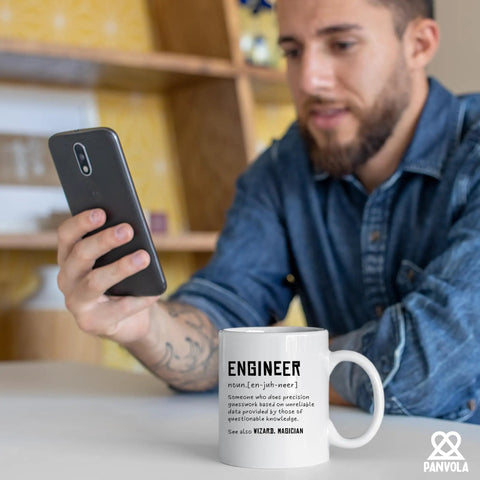 Man holding phone with Engineer Definition Funny Gift Mug For Engineering Students Teachers And Pros 11 Oz White Ceramic