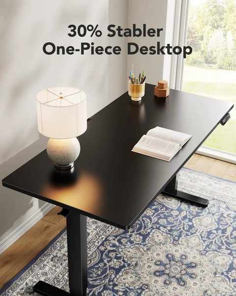 Electric Standing Desk With Real Deal One Piece Desktop Adjustable Height For Sit Stand Four Memory Settings 48 By 24 Inches Heavy Duty Steel Frame Built To Last Home Office Desk Black in a home office with lamp and book on top.