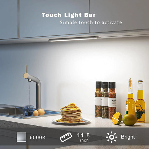 Under Cabinet LED Light Bar 12 Inch Touch Activated And Dimmable Aluminum Fixture For Kitchen Workbench And Desk Cold White 6000K Plug In Silver Finish No Fuss Easy Tap Control illuminating a kitchen counter with spices and fruit.