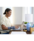 Woman wearing Deluxe Right Hand Wrist Stabilizer Brace With Elbow Support, working on laptop at desk.