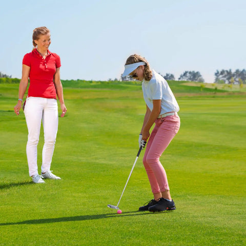 Teen playing golf with Right Hand Golf Putter For Beginners And Teens, 33 Inch Mini Golf Set, instructor watches on a course.