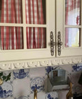 Antique Bronze Vintage Style Cabinet Knobs Set on white kitchen cabinet with red checkered curtains and decorative tiles.
