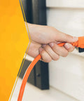 Lite Duty Outdoor Extension Cord For Landscaping And Yard Tools 16 Gauge SJTW Vinyl Jacket Molded Plug Bright Orange Finish 100 Foot Length For Safe Power On Lawn Equipment in use, plugged into outdoor socket.