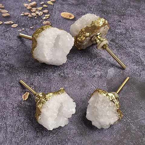 Set Of Natural White Quartz Geode Cabinet Knobs With Gold Plated Drawer Pulls Unique Irregular Crystal Stone Hardware on a dark surface.