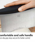Image of a hand holding a stainless steel all purpose scraper and dough cutter for pizza bread and cookie dough, vegetable chopper with built in quarter inch markings, dishwasher safe kitchen essential for precise prep.