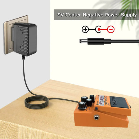 Versatile 9V Guitar Pedal Power Supply Adapter with stable 0.5A DC output, 2.1x5.5mm plug connected to effects pedal on table.