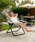 Woman relaxing outdoors on Three Position Adjustable Folding Recliner Chair With Ottoman And Armrests For A Comfy Portable Lounge You Can Use In Living Room Bedroom Office Or Balcony In Gray