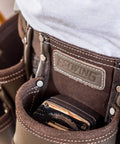 Close-up of a heavy duty leather tool apron with seven pockets, hammer holder, and rivet reinforced edges for pro grade toughness.