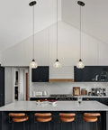 Three Light Matte Black Pendant Lighting With Transparent Glass Shades above modern kitchen island with stools