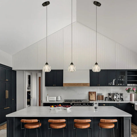 Three Light Matte Black Pendant Lighting With Transparent Glass Shades above modern kitchen island with stools