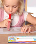 Child using a red blower pen next to 40 Pack Self Adhesive Nameplate Pockets for Desks, Clear 18.9 x 4.7 Inch Outer Pocket Size