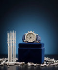 Five Piece Silver Movement Crown Kit For NH35 NH36 NH38 NH39 Watches displayed with a watch on blue stand