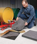 Man using Premium Oil Absorbent Mat Pads 15 x 20 Inches, Heavy Duty 28 Oz Absorbency Per Pad for spill cleanup near drums.