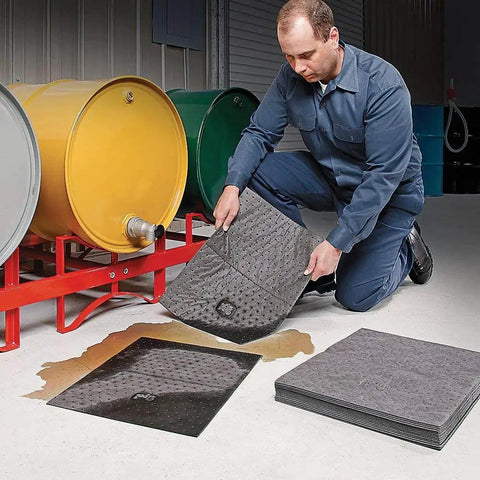 Man using Premium Oil Absorbent Mat Pads 15 x 20 Inches, Heavy Duty 28 Oz Absorbency Per Pad for spill cleanup near drums.