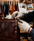 Top Shelf Solid Brass Nailhead Studs With A Killer Gold Shine Featuring No Fuss Flat Head Screw Back Rivets Made For Heavy Duty Leather Handbag Fixes And Smooth Diy Craft Projects That Truly Deliver. Craftsman attaching solid brass studs to brown leather handbag.