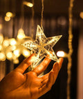 Close-up of hand holding a warm white star from Ramadan Curtain Fairy Lights With Remote, 138 LED 8.2ft By 3.2ft Star And Moon Shaped String Lights