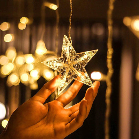 Close-up of hand holding a warm white star from Ramadan Curtain Fairy Lights With Remote, 138 LED 8.2ft By 3.2ft Star And Moon Shaped String Lights