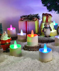 Flameless LED Candles With Remote Timer And Charging Station For Outdoor Use Rechargeable Waterproof RGB Tea Lights Delivering 60 Plus Hours Of Glow Colorful Candles For Valentines Day Halloween Christmas Home Party Decor 12 Pieces in a snowy festive setting with gift boxes and figurines.
