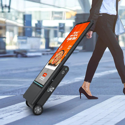55 Inch Outdoor Digital Signage Display Loaded Up With 4K UHD LCD And IP55 Waterproof Shield Boasting 1800 Nits auto brightness, being wheeled by a woman.