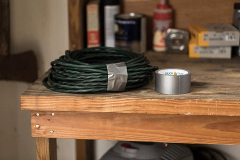 Duck Brand duct tape rolls; two colors (green coil, silver roll) on a wood workbench.