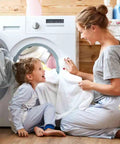 Mother and child doing laundry in front of washing machine, showing family interaction