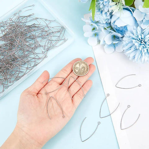 Hand holding stainless steel V shape earring hooks with a coin, part of 200 Pcs V Shape Stainless Steel Earring Hooks 19 Gauge Drop Ear Wires For Jewelry Making DIY Earring Findings Hoops In Handy Box Tarnish Resistant Durable Kit, hooks displayed with flowers.