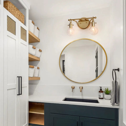 Bathroom with two light gold vanity light with clear glass shades, modern decanter style fixture, mirror, and sink.