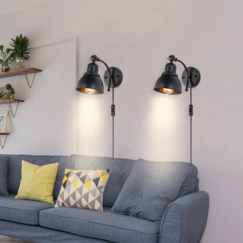 Set Of 2 Black Plug In Wall Sconces Industrial Style With On Off Cord Switch illuminating a cozy living room above a sofa.