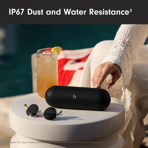 Portable Bluetooth Speaker With Up To 24 Hours Of Battery Life, Water Resistant on table next to sunglasses and drink
