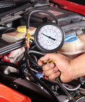 Front view of BETOOLL Pro fuel injection pressure tester gauge 0-140 psi with brass fittings held over car engine bay