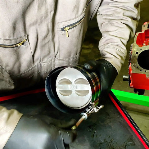 Technician using Adjustable Piston Ring Compressor Tool Fits 3.5 To 7 Inch Pistons With Spring Steel Body And Quarter Inch Drive Adjuster.