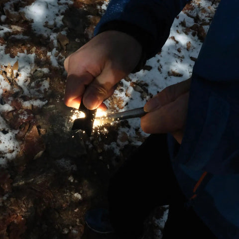 Hands using Beast Fire Starter Survival Kit With Four Ferro Rods In 4 Inch, 3.2 Inch And Two 2.4 Inch Sizes for igniting sparks outdoors.
