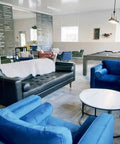 Modern lounge area with blue and black seating, a foosball table, pool table, and white walls showing interior layout.