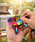 Hands using wooden stick on Camping Scratch Card Kit 24 Pack For Outdoor Parties 12 Unique Designs Revealing Rainbow Colors
