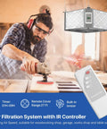 Man using a saw with 360 Degree Intake Air Filtration System For Woodworking With Built-In Ionizer, 1350 CFM and remote control visible